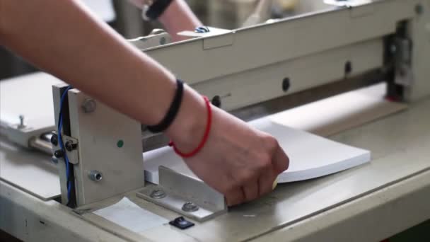 Fermez les mains de la femme coupant des feuilles de papier dans la machine de découpe manuelle de papier . — Video