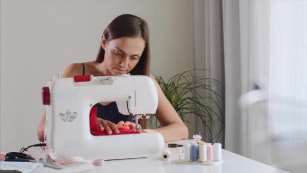 Mujer costurera autónoma que trabaja y cose tela en la máquina de coser . — Vídeos de Stock