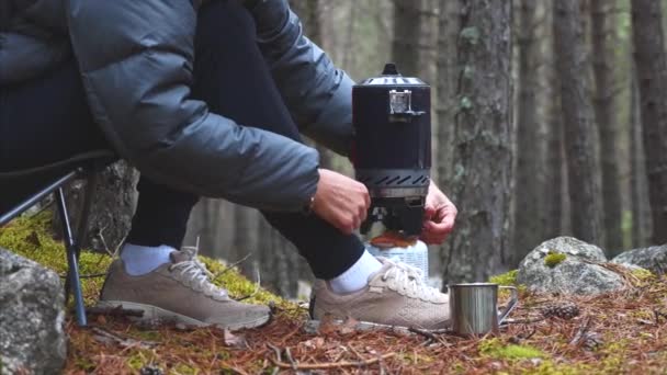 Woman uses gas burner to warm tea in forest camping having break during hiking. — Stock Video