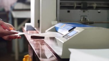 Kadın tipografide laminasyon makinesi laminatöründe kağıt lamine ediyor.