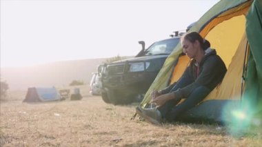 Genç kadın keşif kampında turist çadırı yakınında bir ayakkabı koymak ve gider