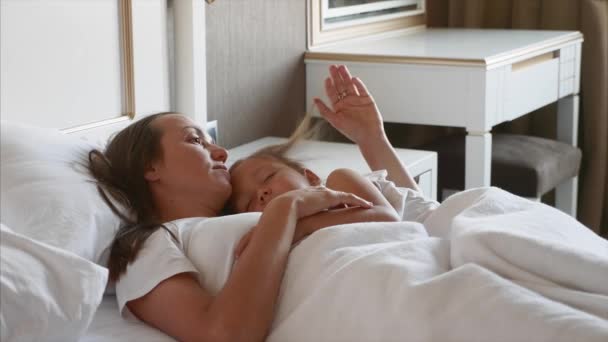 Мати лежить на ліжку зі своєю спальною дитиною, вдома . — стокове відео