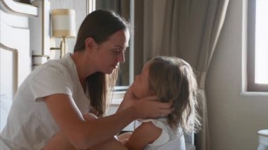 Genç anne evde yatak odasında küçük kızı okşadı