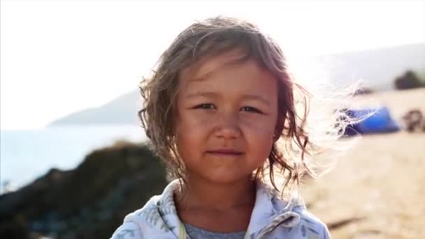 Portrait of little child girl looking at camera outdoor in windy weather. — Stock Video