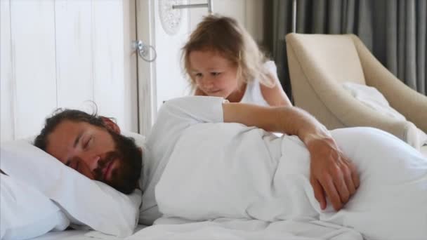 Little daughter comes to sleeping father, wakes him and lies down beside him — Stock Video