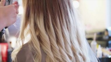 Kuaför güzellik salonunda kadın müşteri için bukleler yapıyor.