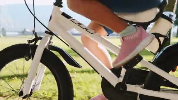 一个小女孩骑着一辆白色的自行车，特写双脚侧视图. — 图库视频影像