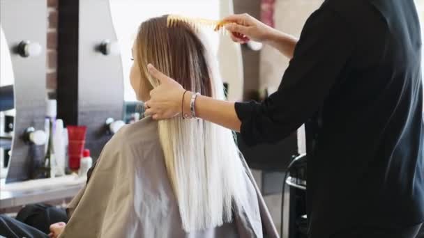 Uma jovem está no cabeleireiro . — Vídeo de Stock