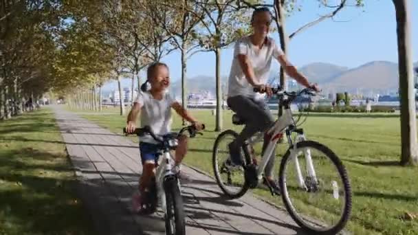Moeder en dochter rijden een fiets langs de kust samen, Steadicam schot — Stockvideo