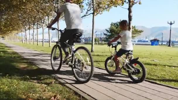 Madre e hija está montando una bicicleta a lo largo del paseo marítimo juntos, steadicam tiro — Vídeo de stock