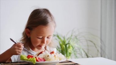 Küçük bir çocuk kız evde spagetti yiyor.
