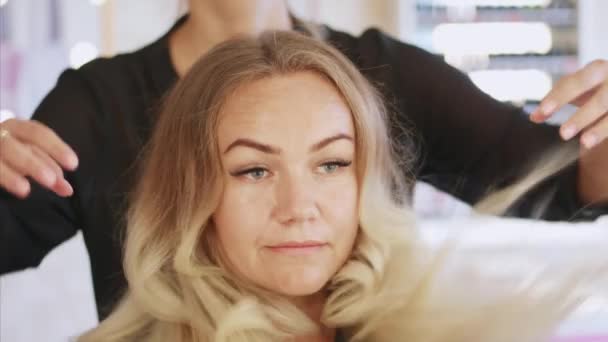 Portrait of a woman in beauty salon. She is looking in the mirror at the hair. — Stock Video