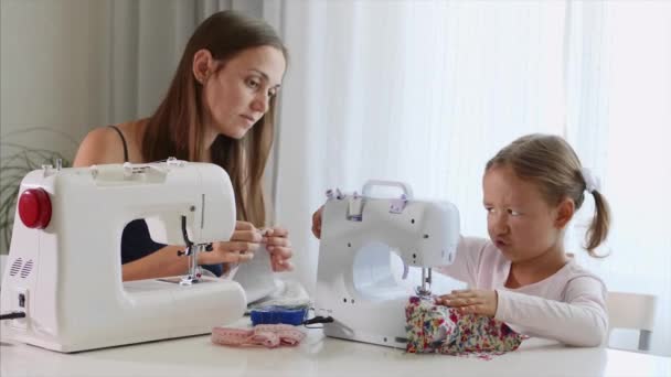 Uma rapariga está a costurar numa máquina. A mãe mostra como trabalhar com equipamentos. Close-up . — Vídeo de Stock