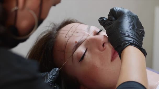 El proceso de dar forma a las cejas con un hilo para una dama, primer plano de una cara . — Vídeo de stock