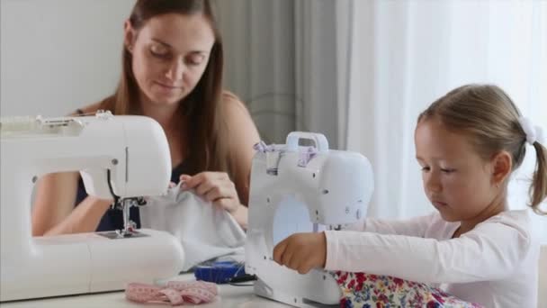 Een meisje is naaien op een machine. Moeder laat zien hoe te werken met apparatuur. Close-up. — Stockvideo