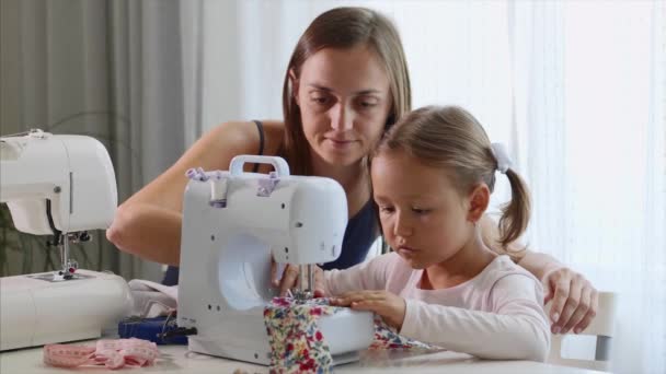 Een meisje is naaien op een machine. Moeder laat zien hoe te werken met apparatuur. Close-up. — Stockvideo
