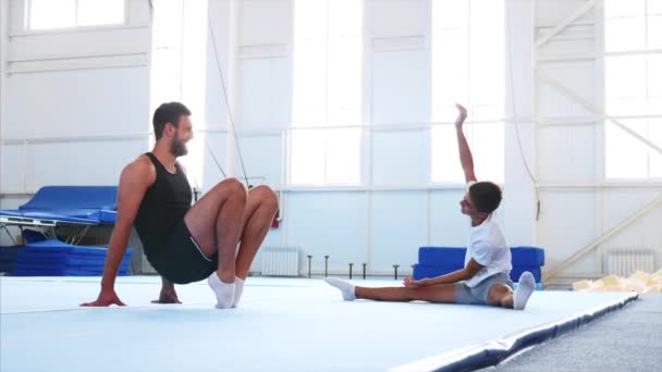 Un athlète homme étire les pieds et un adolescent étire le corps . — Video