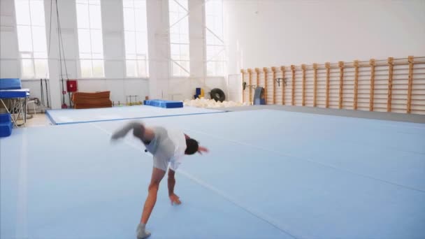 En tonåring pojke gör en kärrhjulsluster och en Triple back flip i gymmet, Steadicam. — Stockvideo