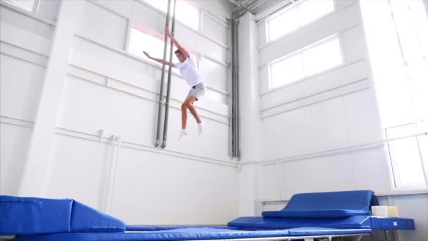 Un giovane atleta fa un doppio twist flip, atterra a piedi. Vista laterale, rallentatore . — Video Stock