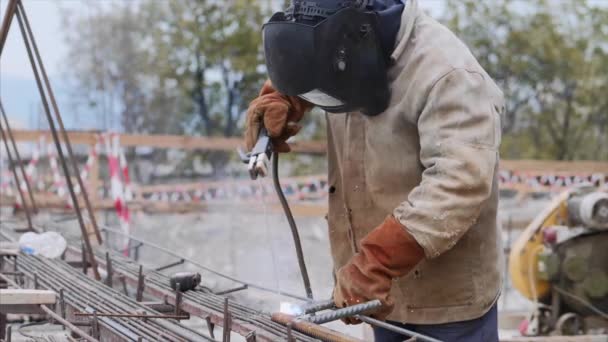 Lasser op bouwplaats is lasbuis met elektrode in helm. — Stockvideo