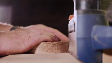 Zanaatkar ahşap atölyesinde öğütme makinesiyle çalışıyor, elleri yakın..