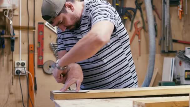Αρσενικό ξυλουργός με μολύβι και χάρακα ιχνηλάτηση της γραμμής κοπής σε μια ξύλινη λεπτομέρεια — Αρχείο Βίντεο