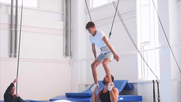 Een Slow Motion van een jonge atleet doen een lucht terug flip over veiligheid stroppen — Stockvideo