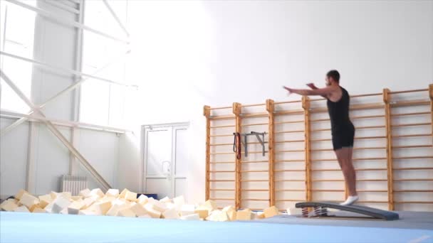 L'athlète court, saute sur un trampoline acrobatique, fait un flip avant, ralenti . — Video