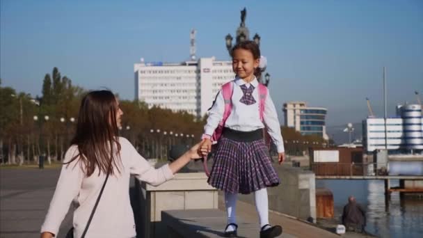 Шкільна дівчина ходить по перилах набережної з мамою, стедікамом, вид спереду . — стокове відео
