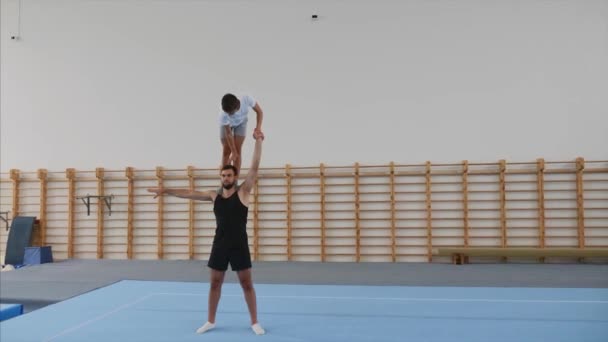 Atleet maakt een handstand met één hand op het hoofd van partner, Steadicam. — Stockvideo