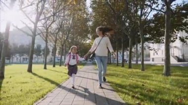 Genç anne ve el ele tutuşan, koşan ve gülümseyen bir kız. steadicam, ön görünüm.