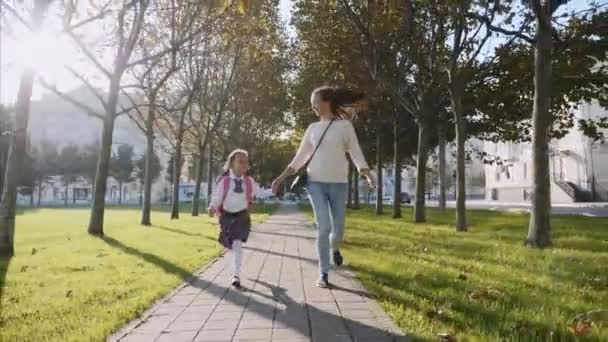 Jovem mãe e uma menina de mãos dadas, correndo e sorrindo. steadicam, vista frontal . — Vídeo de Stock