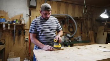 Erkek marangoz doğramacıda elektrikli zımpara makinesiyle çalışıyor.