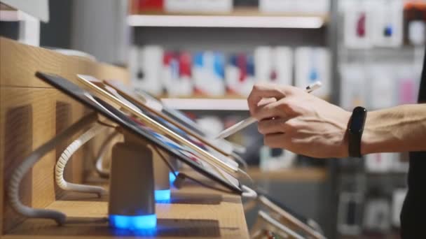 Hombre irreconocible un intento de una tableta con lápiz en una tienda de electrónica — Vídeos de Stock