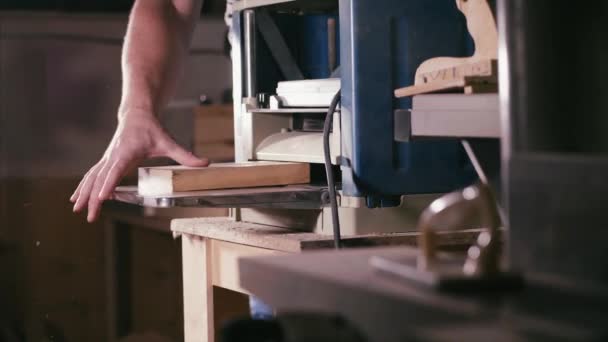 Мужской плотник работает с кабинетной строгальной машиной в деревообрабатывающей мастерской — стоковое видео