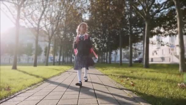 Jeune fille en uniforme scolaire marche dans le parc par temps ensoleillé, steadicam . — Video