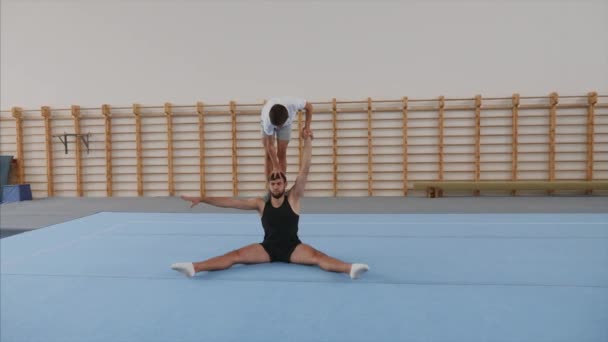 Young athlete is making handstand and front split on head of partner. Steadicam — Stock Video