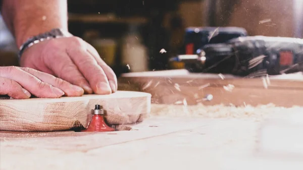 A carpenter is chamfers an edge from a compartmental dish on milling cutter — Stock Photo, Image
