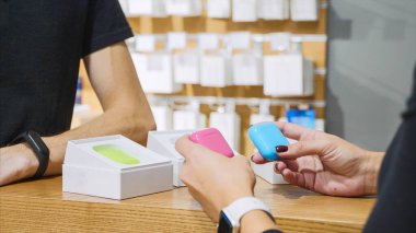 Tanınmayan bir kadın elektronik mağazasından kulaklık seçiyor.