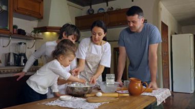 Çocuklar, aile mutfağında hamuru hazırlamaya yardım ediyor.