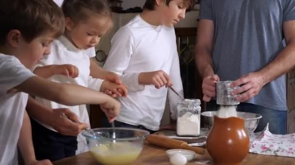 Kinderen helpen ouders bij het maken van een deeg in de huiselijke keuken — Stockvideo