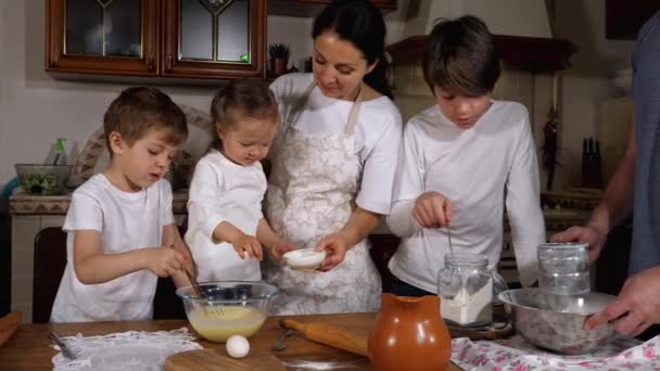 Kinderen helpen ouders bij het maken van een deeg in de huiselijke keuken — Stockvideo