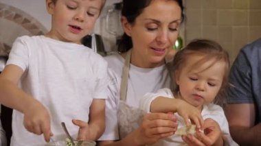 Ailesi olan çocuklar ev mutfağında hamur tatlısı hazırlıyorlar.