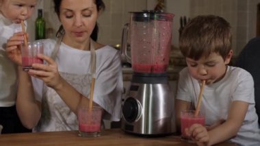 Ailesi olan çocuklar evdeki mutfakta smoothie hazırlayıp içiyorlar.