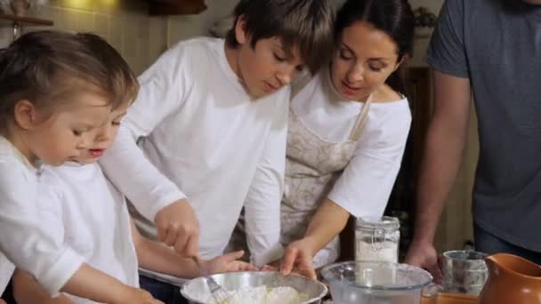 Kinderen helpen ouders bij het maken van een deeg in de huiselijke keuken — Stockvideo