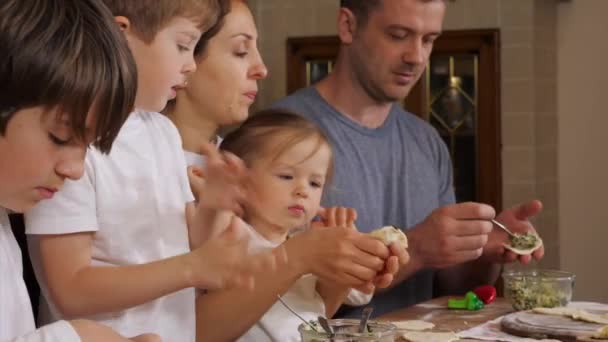 Дети с родителями готовят пельмени на домашней кухне — стоковое видео