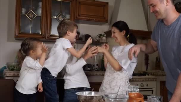 Crianças ajudando os pais a preparar uma massa na cozinha doméstica — Vídeo de Stock