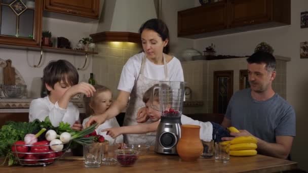 両親と一緒に家庭のキッチンでスムージーを準備している子供たち — ストック動画