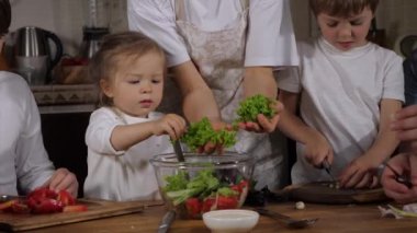 Üç çocuklu mutlu bir aile evde salata pişiriyor.