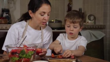 Oğulları olan anne taze salata yapıyor. 